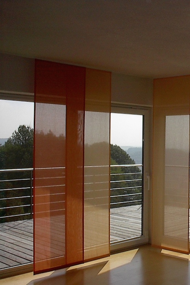 Die Schiebegardienen in warmen Farben bieten einen Blick- und Sonnenschutz und lassen den Raum trotzdem hell erscheinen.